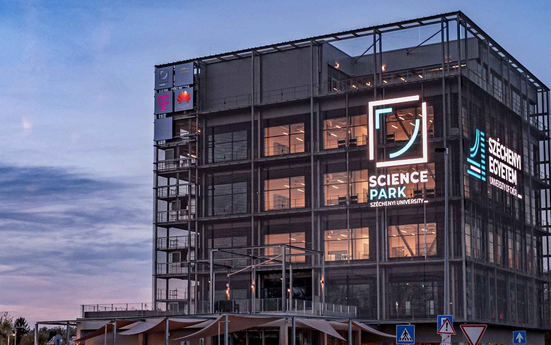 A Kocka épülete alkonyatkor, a homlokzaton a Science Park és a Széchenyi Egyetem világító logójával